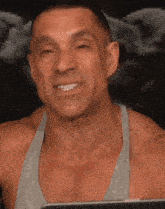 a man in a grey tank top is smiling