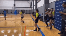a group of people are playing basketball in a gym with a wall behind them that says m & m