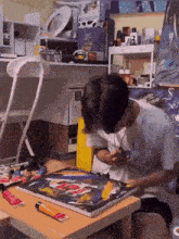 a man is sitting at a table painting a picture