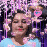 a woman in a blue shirt is surrounded by pink hearts and sparkles