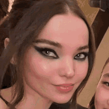 a close up of a woman 's face with smokey eyes and a smile on her face .