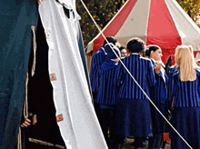 a group of people in blue and white striped uniforms are standing outside a tent