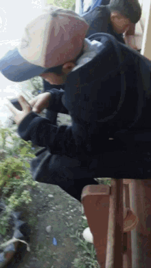a man wearing a hat with the letter s on it is looking at his phone
