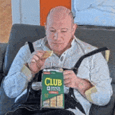 a man sitting on a couch eating club snack stacks chips