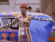 a man in a clown costume is standing next to a car