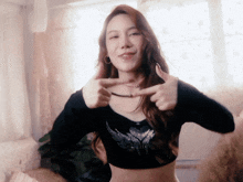 a woman wearing a black crop top is giving a thumbs up