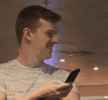 a man is smiling while holding a cell phone in his hand