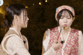 a woman in a floral vest is holding a knife to her mouth
