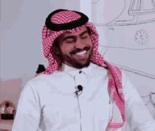 a man wearing a white shirt and a red and white head scarf is smiling