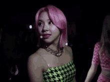 a woman with pink hair is standing in a crowd of people .
