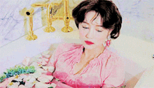a woman in a pink dress is laying in a bathtub full of flowers