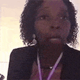 a woman with curly hair is wearing a purple lanyard around her neck and earrings .