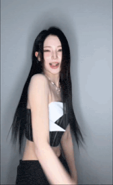 a woman with long black hair wearing a black and white top