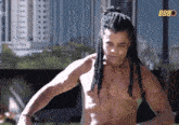 a shirtless man with dreadlocks is standing in front of a sign that says bbb