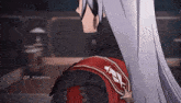 a person with long white hair is wearing a red jacket and a red sash .