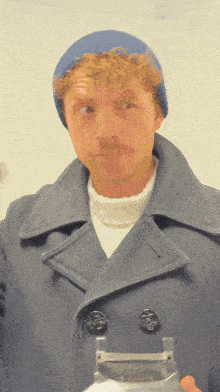 a man wearing a blue hat and a blue coat is holding a bottle