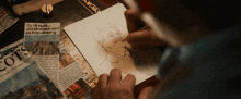 a man is drawing a picture of a man on a piece of paper that says cots on it