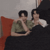 a man in a green shirt sits next to another man in a white shirt