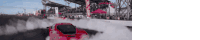 a red car is drifting on a track with smoke coming out of it .