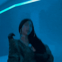 a woman with long black hair wearing a green jacket