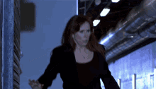 a woman walking down a dark hallway with a necklace on her neck