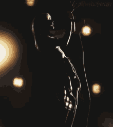 a person is singing into a microphone in a dark room with lights behind them and the words " alltimeloudtrencher " visible