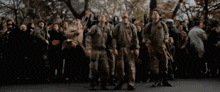 a group of people in military uniforms are standing in front of a crowd looking up .