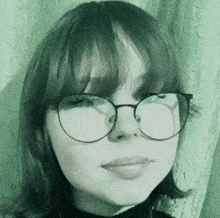 a young girl wearing glasses and a black turtleneck is smiling