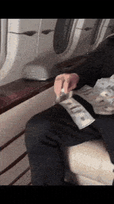 a man is sitting on a plane holding a stack of money