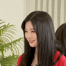 a woman with long black hair and a red shirt smiles