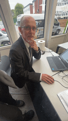 a man sitting at a desk with a laptop and a roll of toilet paper