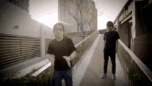 two men standing on a walkway with the sun shining through the buildings behind them