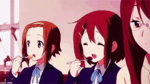 a group of anime girls are eating food with spoons in their mouths .
