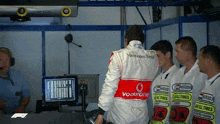 a man wearing a mercedes benz jacket is standing in a garage