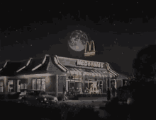 a mcdonald 's restaurant at night with a full moon in the background