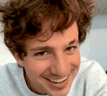 a man with curly hair is smiling for the camera .