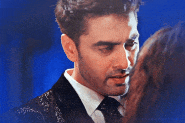 a man in a suit and tie is looking at a woman in a blue background