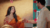 a man and a woman are holding hands and looking at each other .