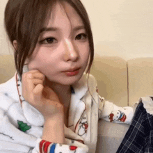 a woman is sitting on a couch with her hand on her chin .