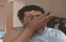 a man covering his face with his hand in a kitchen .