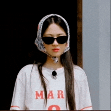 a woman wearing sunglasses and a scarf around her head has a t-shirt that says mar on it