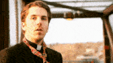 a man wearing a clergy collar and a tie looks at the camera