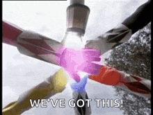 a group of power rangers are putting their hands together in a circle and saying `` we 've got this '' .