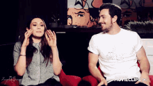 a man and a woman are sitting next to each other and the man has a movieclips shirt on