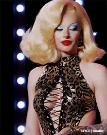a woman with blonde hair and red lips is wearing a leopard print top with a plunging neckline