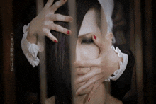 a woman is behind bars with her hands on her face .