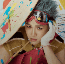 a young man with blue hair and goggles holds a palette
