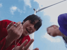 a man in a red shirt is giving the middle finger to another man in a blue hat