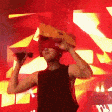a man in a black tank top is holding a microphone in front of a red background