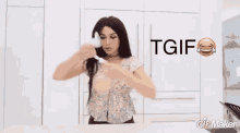 a woman in a floral shirt is holding a white object in front of a sign that says tgif